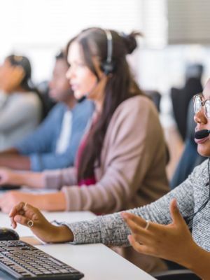 Customer service employees at their desk talking to customers in front of computers