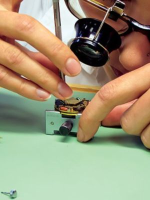 An AJS attendee in the AWCI watch class examining a movement through a loupe